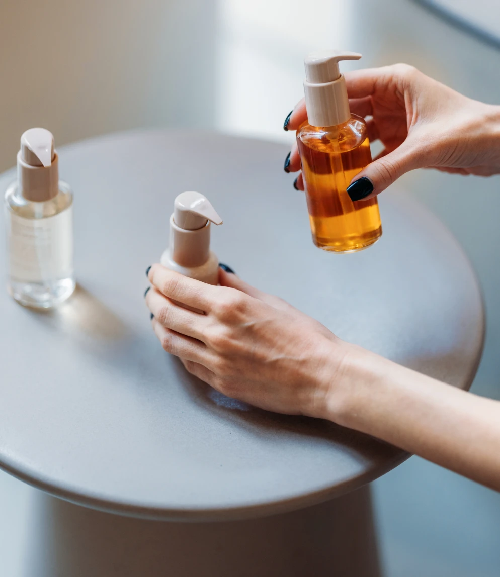 Hands holding skincare bottles on table