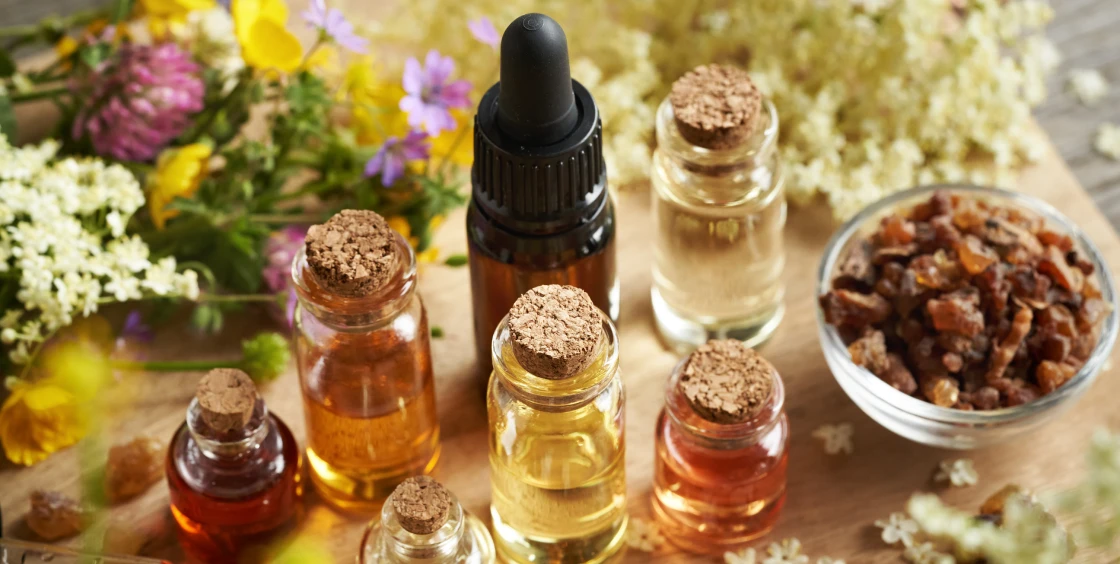 Essential oils and flowers on wooden table